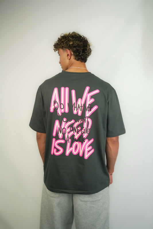 Calgary-based streetwear t-shirt by HRTBRK with neon pink lettering “All We Need Is Love” and handwritten graffiti-style overlays, back view.