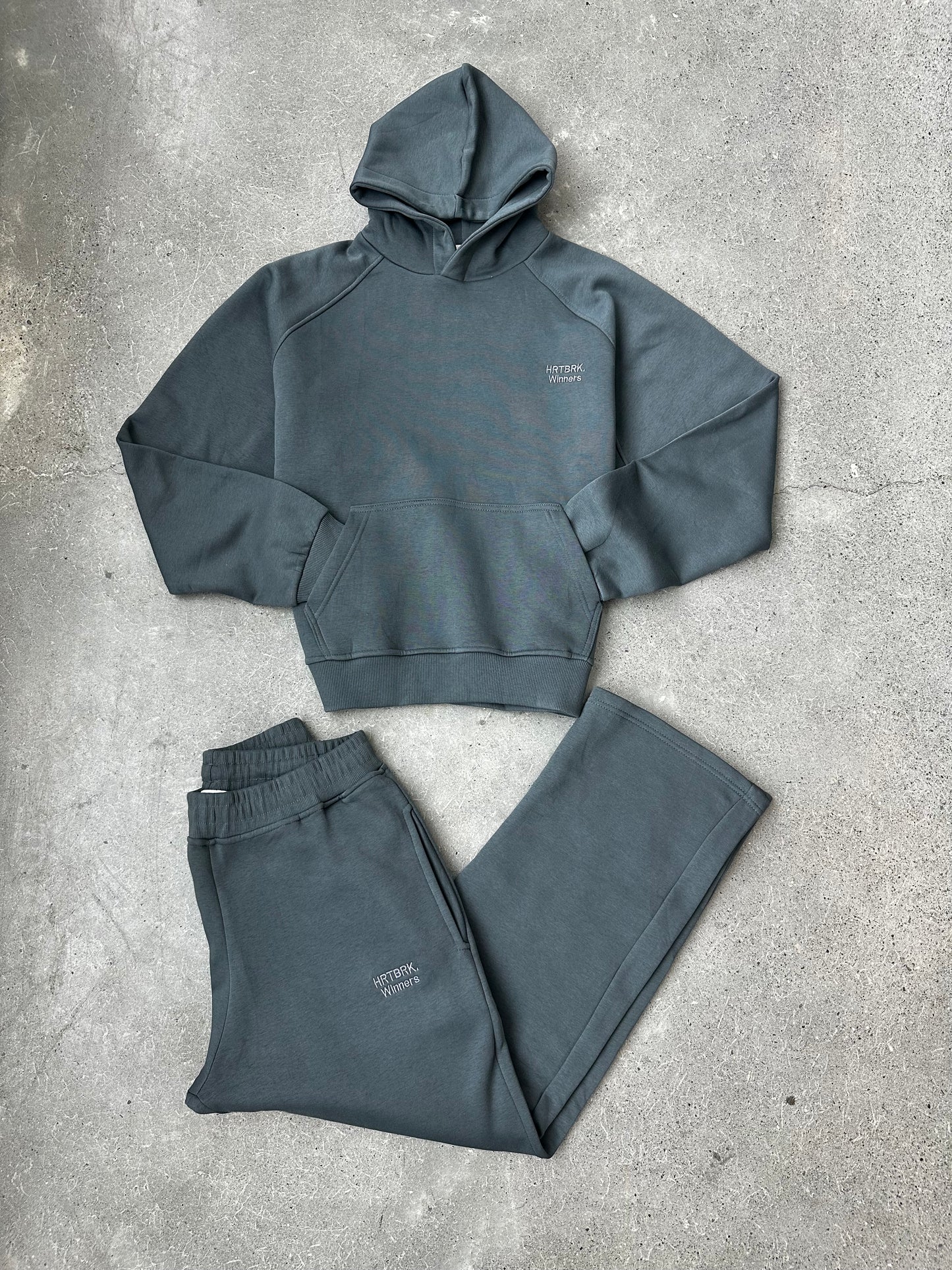 Gray hoodie and pants set on a concrete surface
