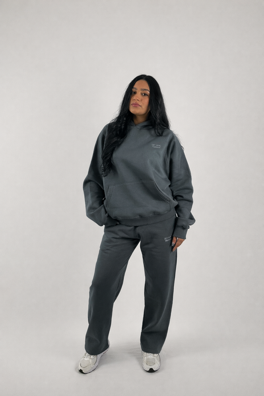 A girl model wearing a gray tracksuit on a white background